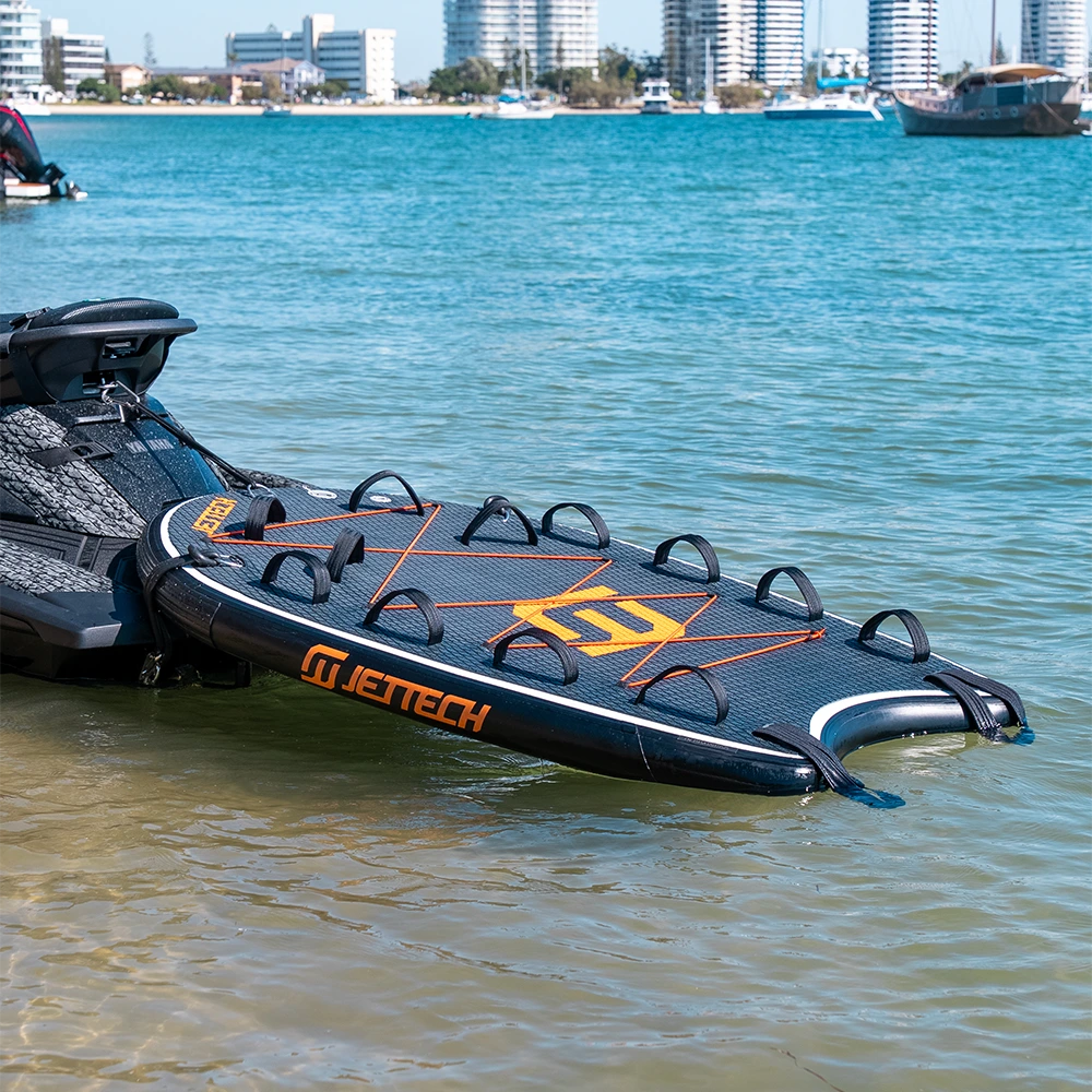 Inflatable water board with 'jettech' branding on a body of water with buildings in the background.
