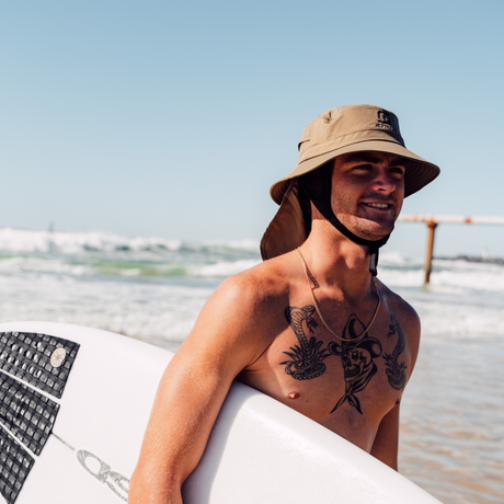 man wearing water proof surf hat holding surf board