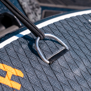 Close-up of a metal ring on a textured surface with a brand logo.