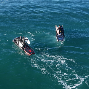 Two jet skis on a body of water with people on board