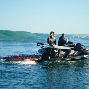 Two people on a jet ski with a surfboard in the ocean