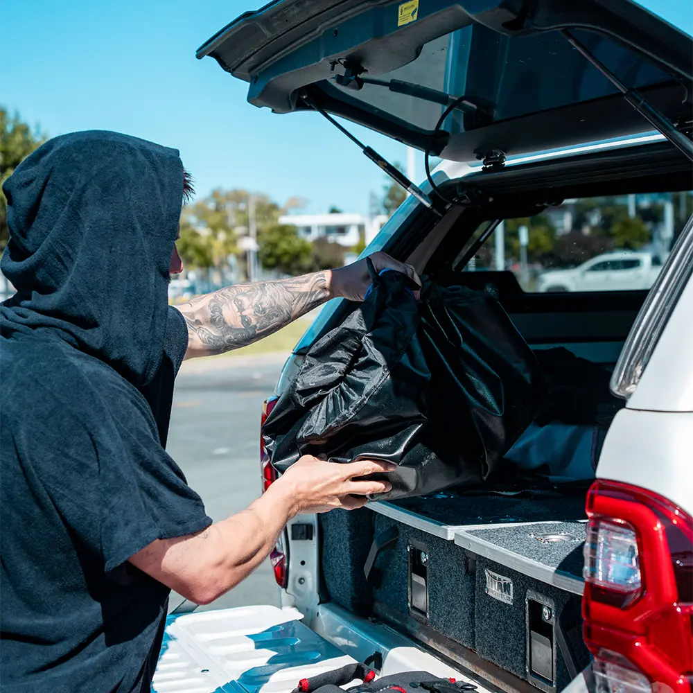 Person loading items into the back of a white SUV with an open tailgate.