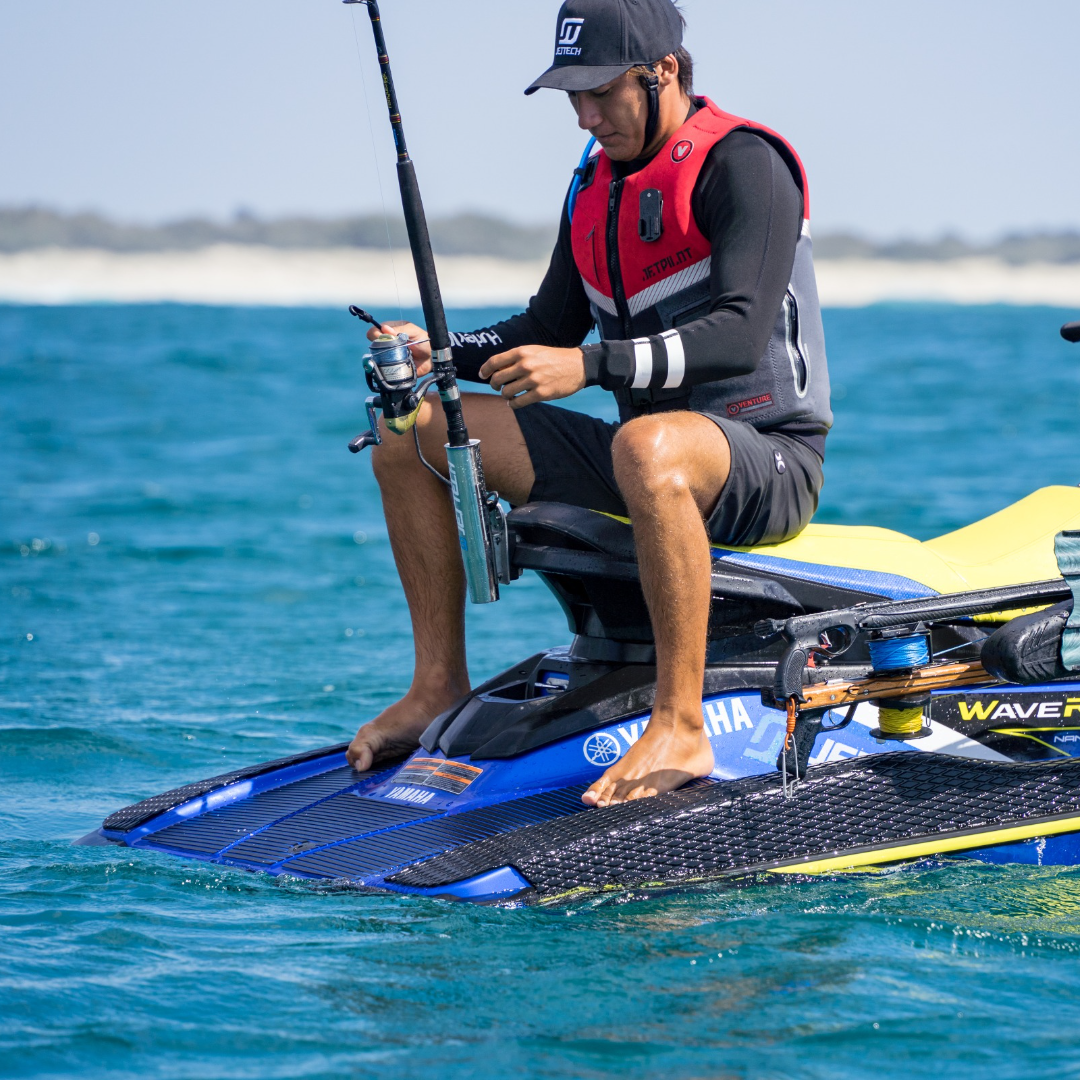 man sitting on jet ski with fishing rod