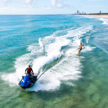 man holding rope being pulled into surf break